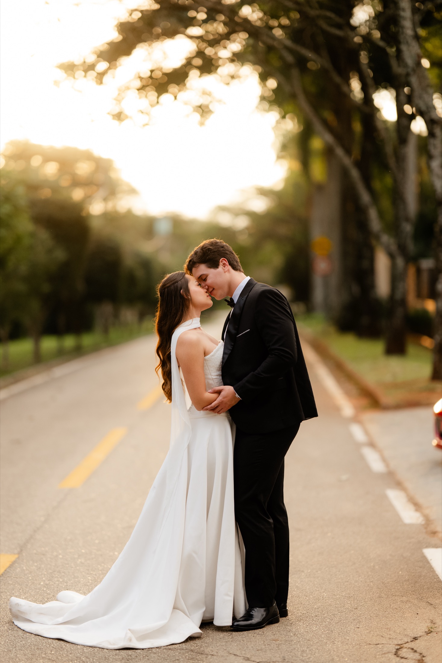 Nicolas e Mariane se beijam em uma estrada cercada por árvores.